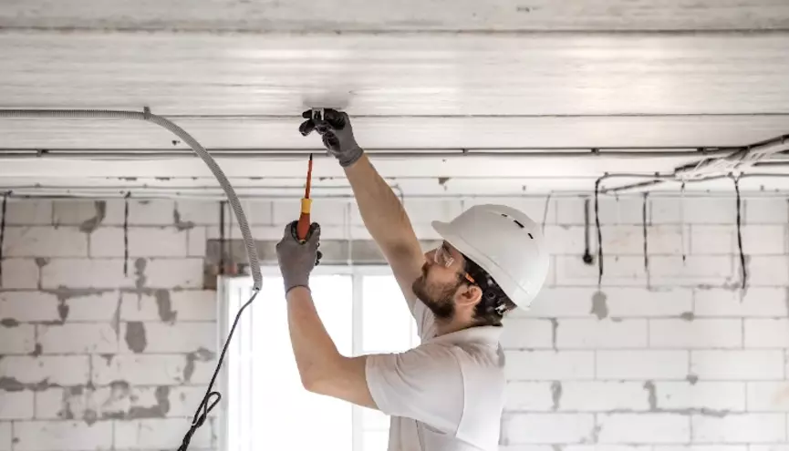 Elektrik&aacute;ř upevňuje kabely na strop